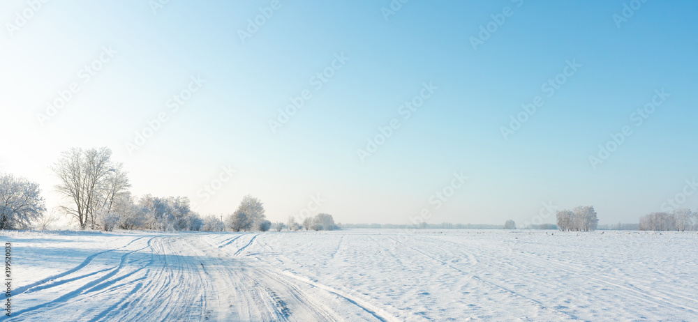 Snow covered winter field with trees and road going through to the horizon. Winter landscape. Beautiful winter nature. Snow covered winter field with trees and road going through to the horizon. Winter landscape. Beautiful winter nature.
