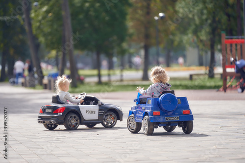Small children drive, ride on children's toy cars. Back view.