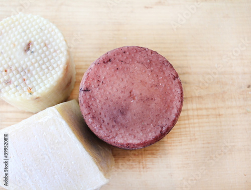 Farmer's cheese crust of cheese with grains inside. the texture as it Matures is handmade. pieces of cheese on a cutting Board in different colors of Derby, caciotta, cheddar