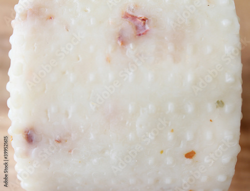 Farmer's cheese crust of cheese with grains inside. texture as hand-made cheeses ripen. orange white green solid background, cheese mold