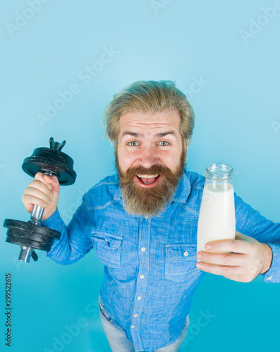 Bearded man with milk dumbbell. Healthy lifestyle. Lactose. Vitamins for muscles. Calcium. Milk products.