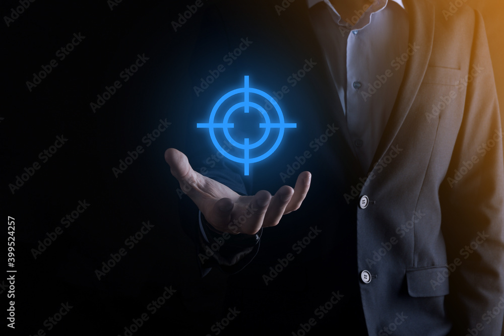 Targeting concept with businessman hand holding target icon dartboard sketch on chalkboard. Objective target and investment goal concept. Targeting concept with businessman hand holding target icon dartboard sketch on chalkboard. Objective target and investment goal concept.