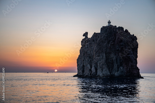 Lighthouse overlooking the sea, on an old inactive volcano, called Strombolicchio. The sunset creates a soft silhouette.