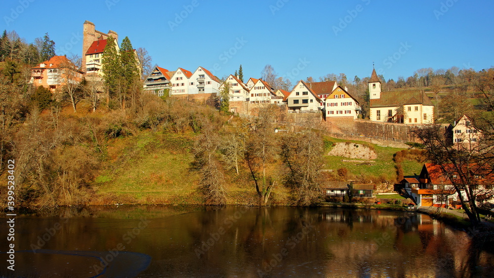 Dorf Berneck mit malerischen Häuserfronten und alter Burg auf hohem Berg  über schönem See in der Sonne
