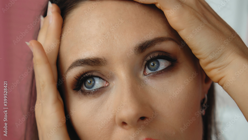 Fototapeta premium Young and beautiful European girl close-up touches the skin of the face with tender hands