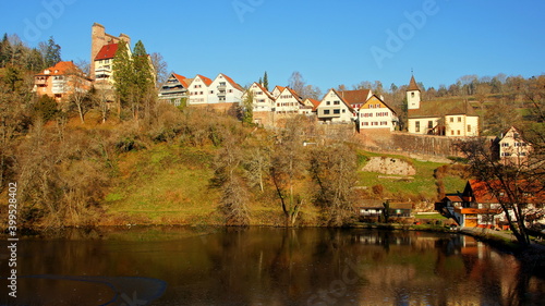 Dorf Berneck mit malerischen Häuserfronten und alter Burg auf hohem Berg über schönem See in der Sonne