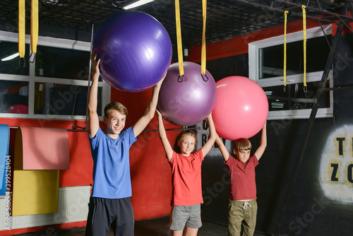 Three children in the gym are engaged with fitness balls.