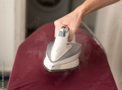 Man hand ironing clothes on iron board.