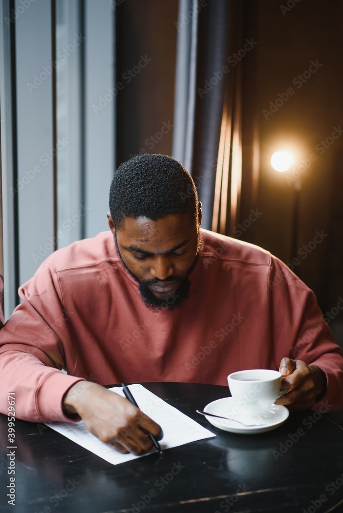 Cheerful young african american student man in headphones using computer in cafe. Online video chat with friends Cheerful young african american student man in headphones using computer in cafe. Online video chat with friends