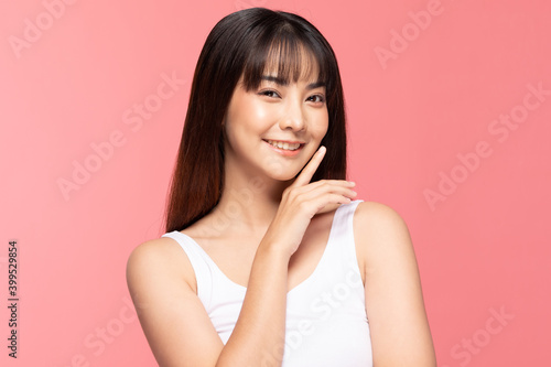 Young Beautiful Asian woman smile touching soft cheek with clean and fresh skin Happiness and cheerful with positive emotional,isolated on pink background,Beauty Cosmetics and spa Treatment Concept