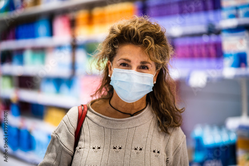 Mature woman smiling to camera while wearing mask in supermarket