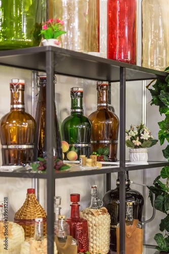 Glass large empty bottles and flasks  for wine and alcoholic beverages on a shelf in a shop window are sold on a shelf