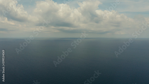 Sea surface with waves against the blue sky with clouds, aerial view. Water cloud horizon background. Blue sea water with small waves against sky.