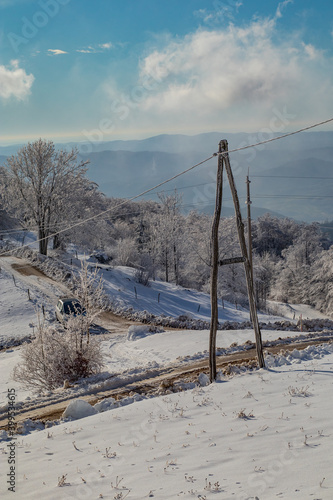 Cold nature covered with snow, with visible sole electric pole defying winds and cold weather. Rural telecommunications.
