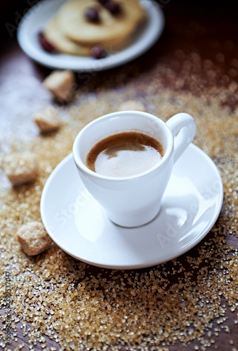 Cup of coffee and brown sugar on wooden background. Close up. 