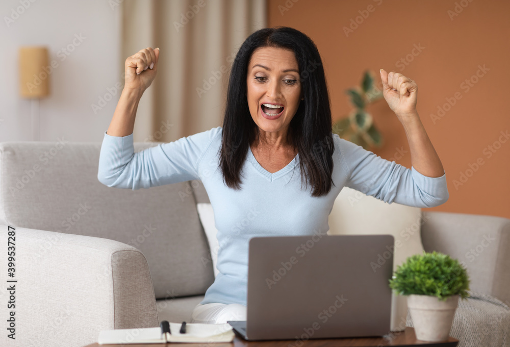 Excited mature woman screaming yes using laptop computer Excited mature woman screaming yes using laptop computer