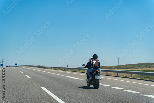 Bike with two riders on desert highway with clear sky and bushes on a summer day