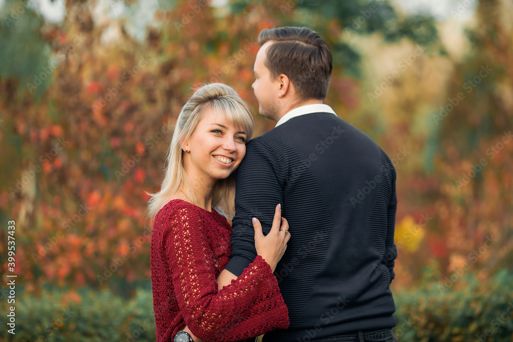 blonde girl in maroon sweater, brown-haired young man in blue sweater hug in the Park blonde girl in maroon sweater, brown-haired young man in blue sweater hug in the Park