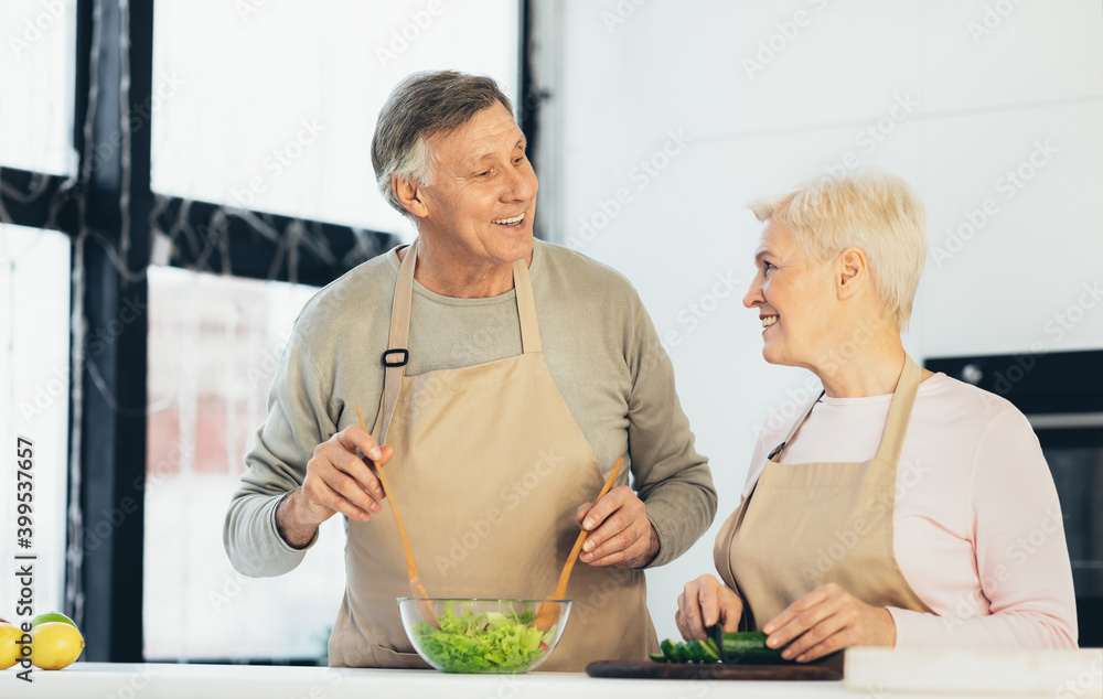 Senior Couple Making Dinner Cooking Smiling Each Other In Kitchen Senior Couple Making Dinner Cooking Smiling Each Other In Kitchen