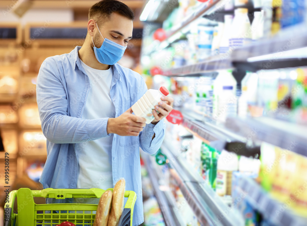 Man in medical mask shopping groceries, buying milk