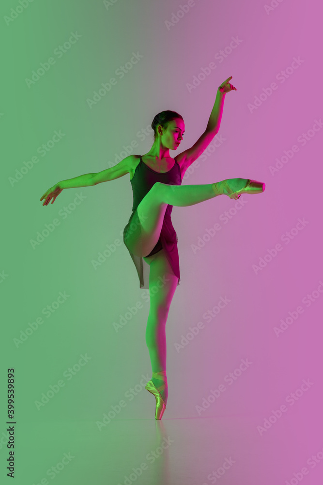 Directive. Young and graceful ballet dancer isolated on gradient pink-green studio background in neon. Art, motion, action, flexibility, inspiration concept. Flexible ballerina, weightless jumps.