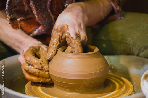 Close up view - professional male potter making pot on pottery wheel at workshop, studio. Handmade, art and handicraft concept