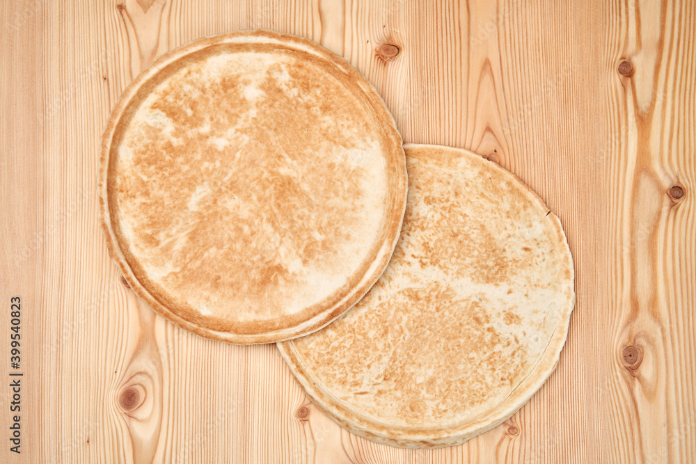 Two flat pizza dough on a wooden table, top view. Two flat pizza dough on a wooden table, top view.