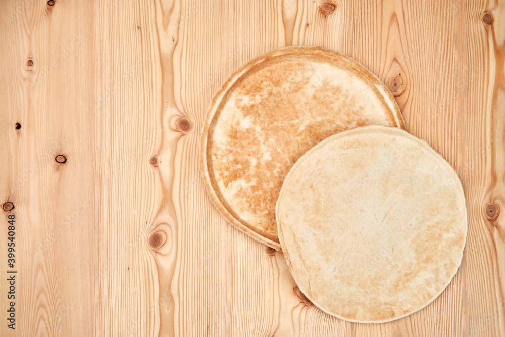 Two flat pizza dough cakes on a wooden table. One lies on the other. Top view with copy space. Two flat pizza dough cakes on a wooden table. One lies on the other. Top view with copy space.