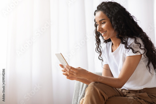 Beautiful smiling woman using mobile phone at home