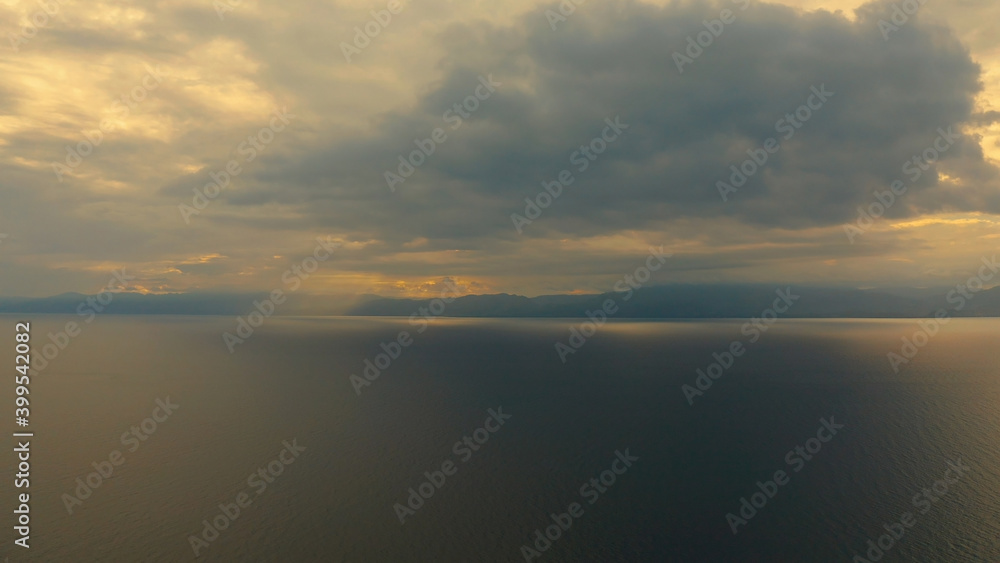 Sunset above the sea surface with waves, top view. Reflected sun on a water surface. Sunset over ocean. Seascape, Summer and travel vacation concept