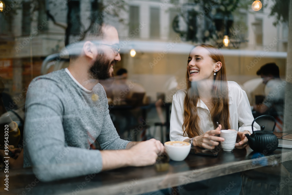 Cheerful young couple enjoying hot beverages in cafe Cheerful young couple enjoying hot beverages in cafe
