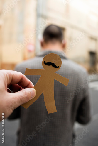 man about to stick a paper man doll to another man photo