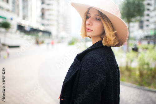 Elegant stylish blonde short hair girl in hat posing over street background © benevolente