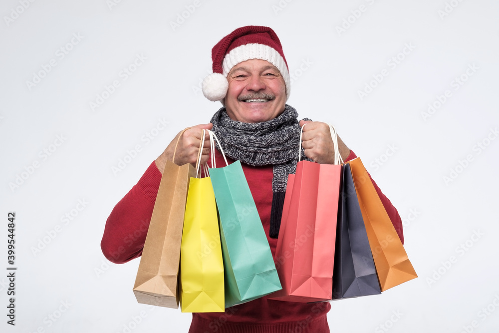 Surprised happy mature man in warm clothing holding paper bags. Studio shot Surprised happy mature man in warm clothing holding paper bags. Studio shot