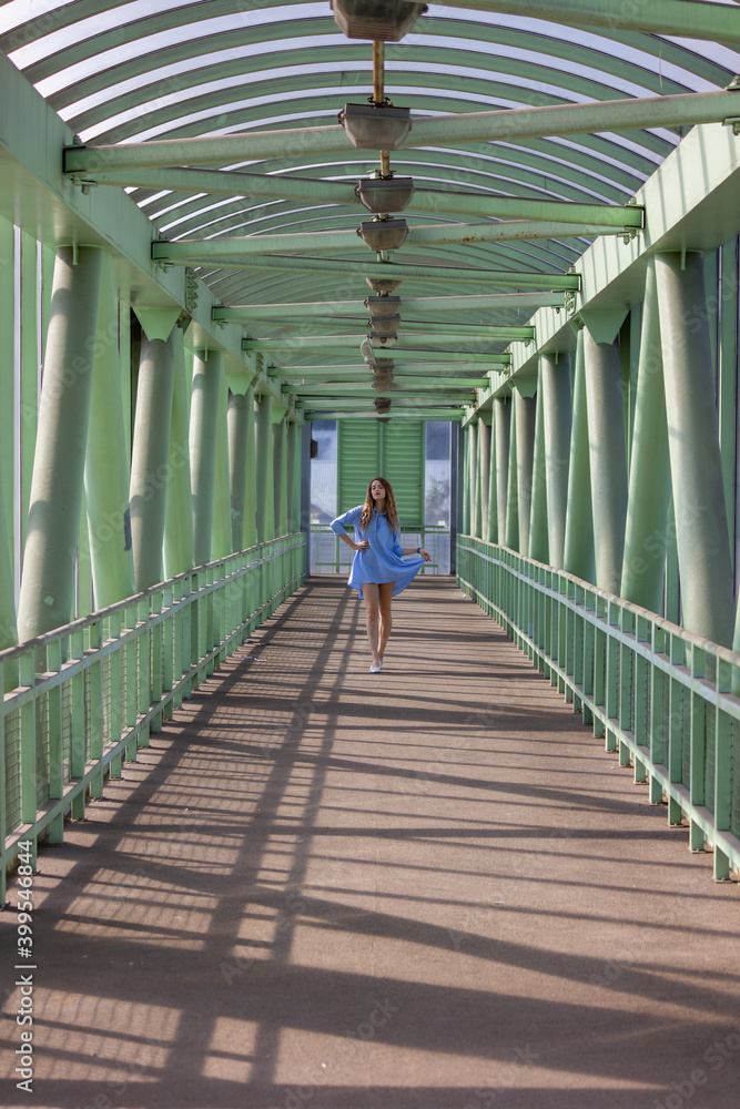A girl in a blue nightgown walks across the bridge.