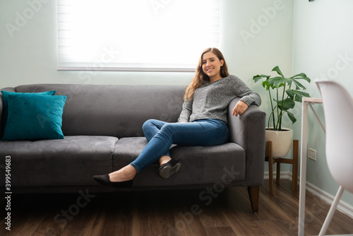 Beautiful young woman smiling and chilling on her couch