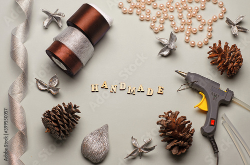 Shiny ribbon, cones, handcraft tool, ribbon beads on a gray background. Winter crafts. Quarantine session. DIY. Handmade.Holiday crafts.Brown colors