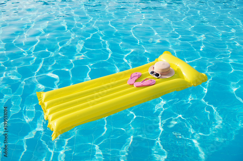 Beach summer holiday background. Inflatable air mattress, flip flops and hat on swimming pool. © nata777_7