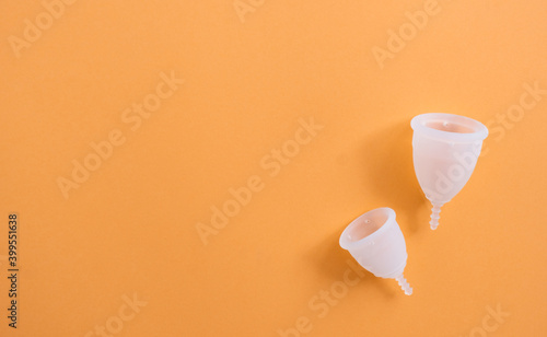 Difference between small and large menstrual cup. Two reusable menstrual cups in different size isolated on color background photo