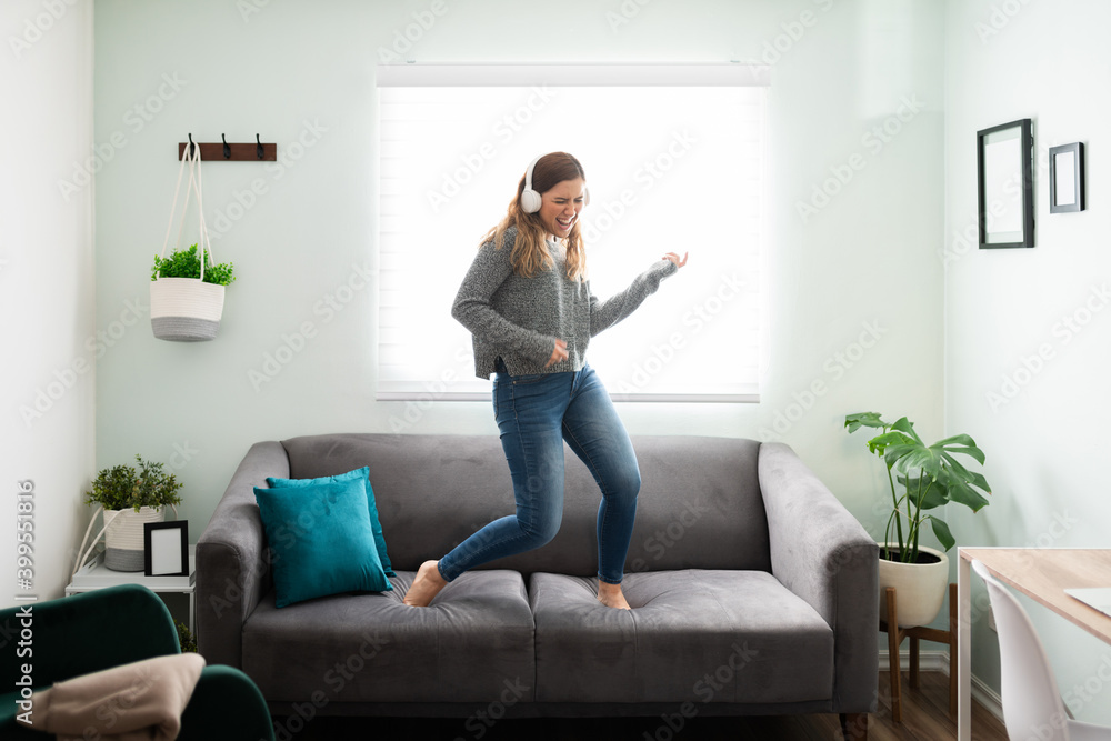 Enthusiastic woman singing with headphones on her sofa