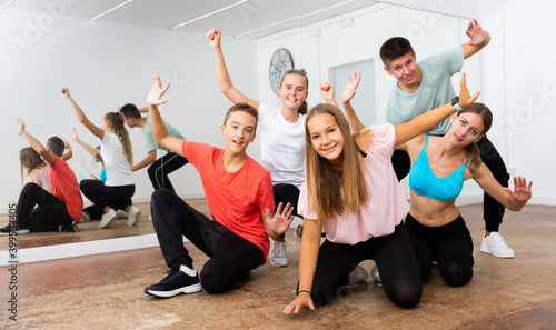 Happy teens posing with young female coach during dance training in modern dance school..