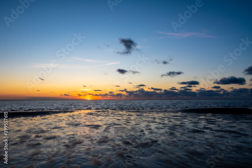 View of the setting sun shining on the Sea and reflected on the beach  clouds with sun-shining edges. Landscape. High quality photo showing concept of freedom and dreams