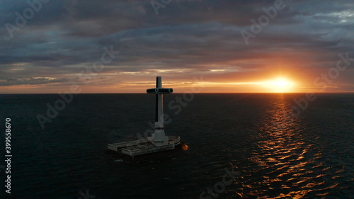 Catholic cross in sunken cemetery in the sea at sunset, aerial view. Colorful bright clouds during sunset over the sea. Sunset at Sunken Cemetery Camiguin Island Philippines.