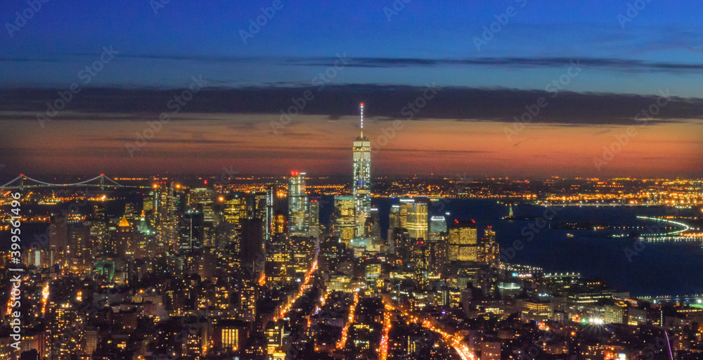 Breathtaking Panoramic and Aerial View of  Manhattan, New York City at Night. Illuminated Buildings After Sunset. Beautiful Crimson Colors in the Sky. Freedom Tower, Lady Liberty Statue, Hudson River.