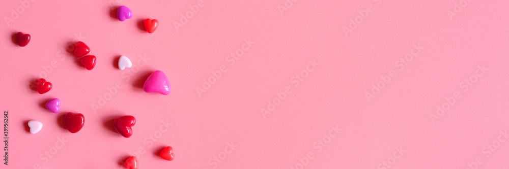 a heap of heart shaped glossy beads in different pink shades on a pink background. banner. space for text a heap of heart shaped glossy beads in different pink shades on a pink background. banner. space for text
