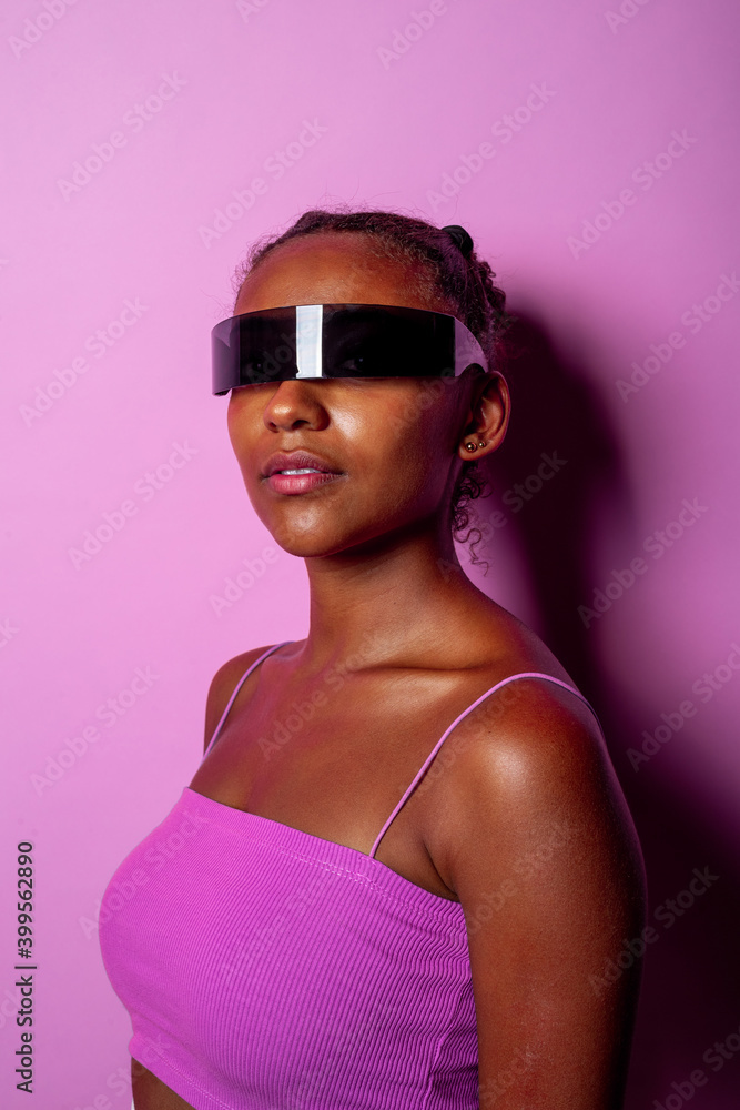 Young black woman wearing sci-fi smart glasses on pink background Young black woman wearing sci-fi smart glasses on pink background