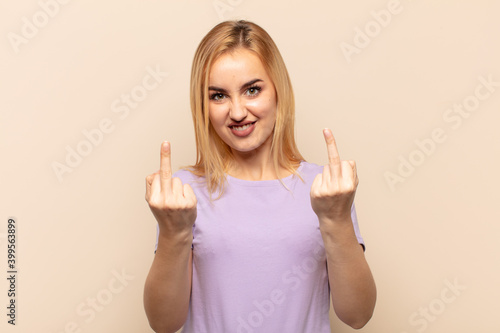 Fotografie young blonde woman feeling provocative, aggressive and obscene, flipping the mid