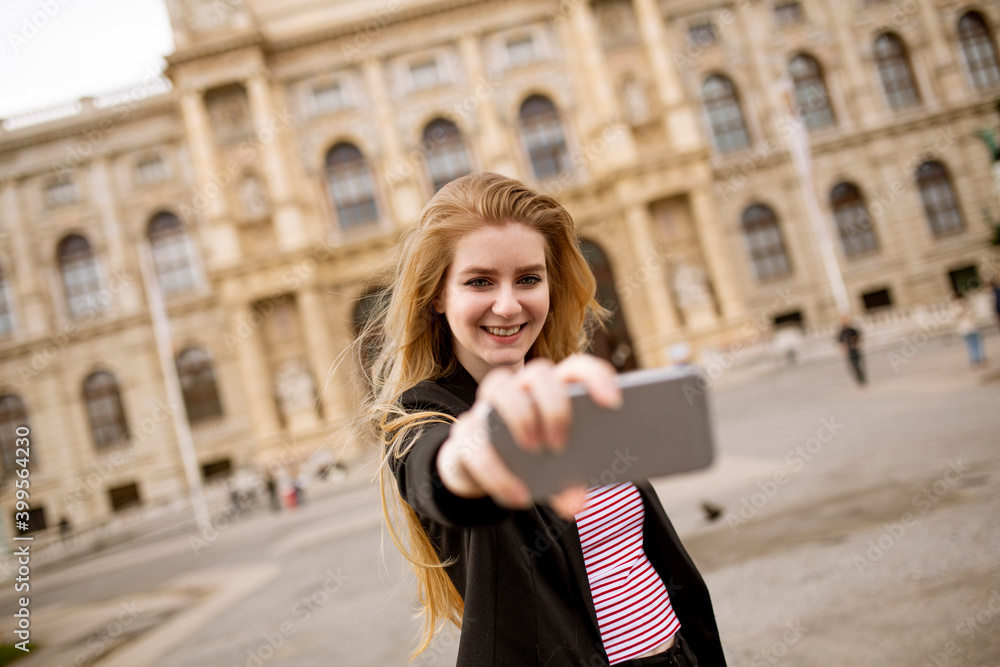 Young female tourist taking selfie with mobile photo in centre of Vienna, Austria
