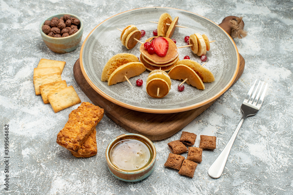 Buttermilk fruit pancakes on wooden cutting board with cookies biscuits honey on blue background Buttermilk fruit pancakes on wooden cutting board with cookies biscuits honey on blue background