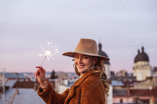 Φωτογραφία Happy smiling woman holding sparkler, posing in European city